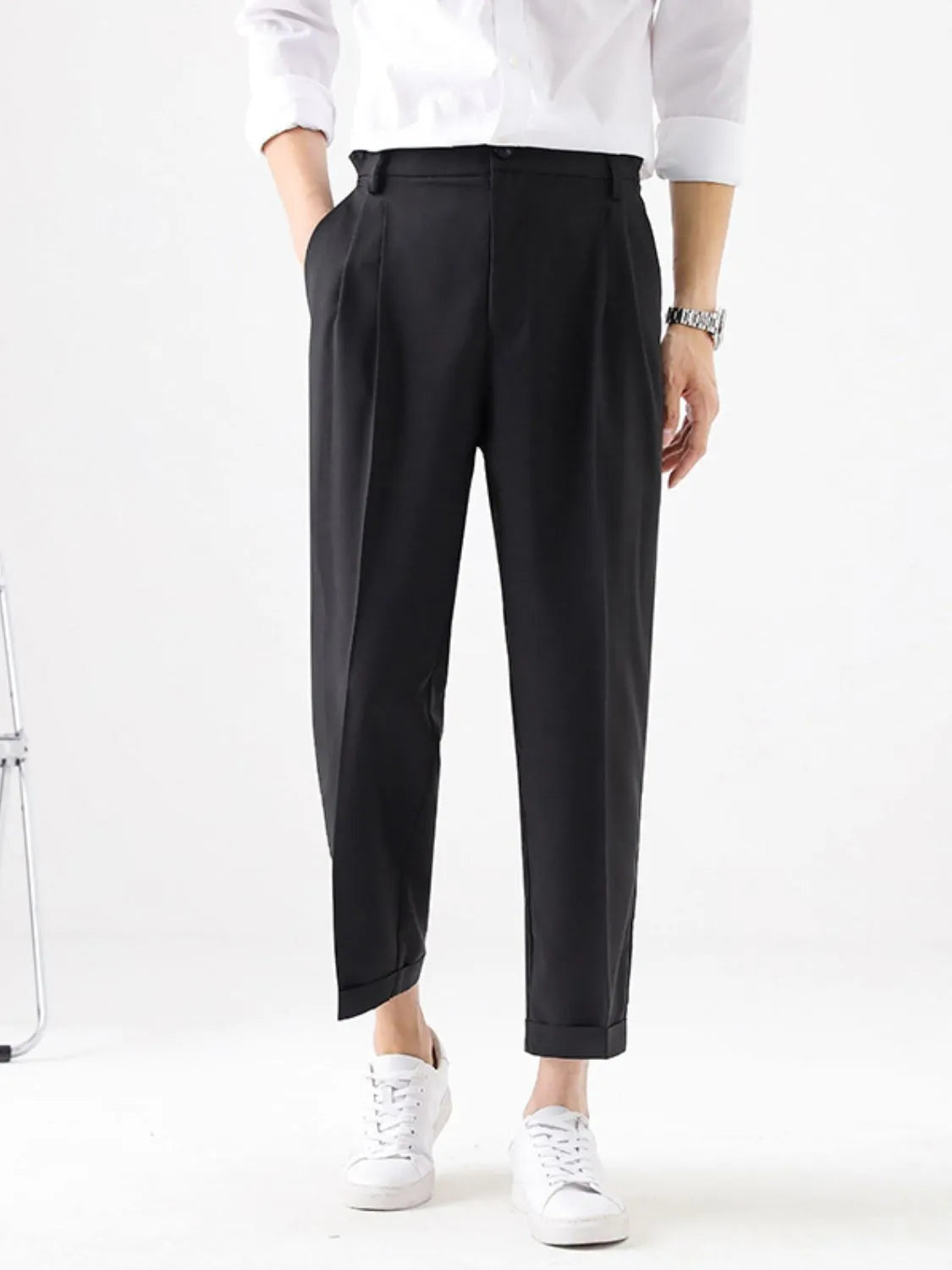 Person wearing black pants and a white shirt on a white background