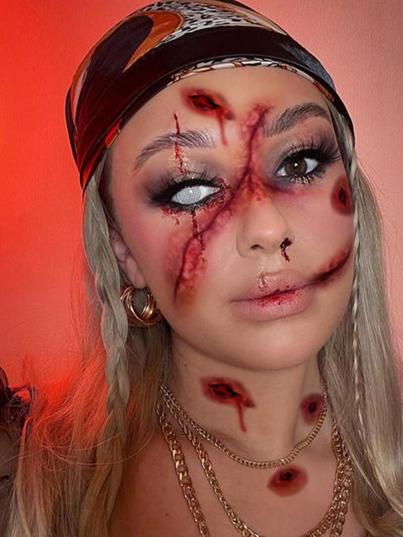 A person with wavy blonde hair and a black headband wears theatrical horror makeup featuring vertical gash-like lines and bruising, creating a zombie-inspired look.