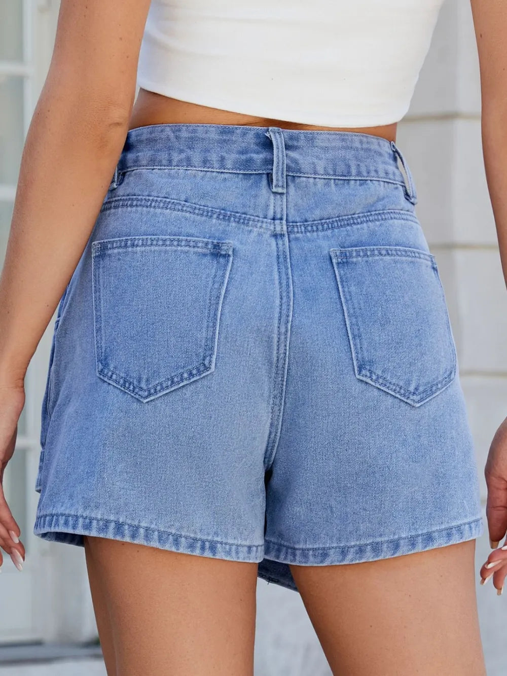 Person wearing light blue denim shorts with a white top.
