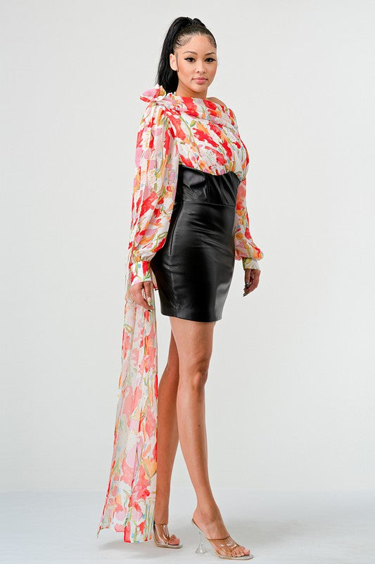 a woman in a black leather mini skirt and a floral print off-the-shoulder top with dramatic sleeves.
