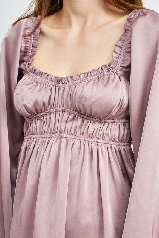 The dress is a puple, long-sleeved mini with a smocked, square-neck bodice and a loose, flowy skirt that falls above the knees.