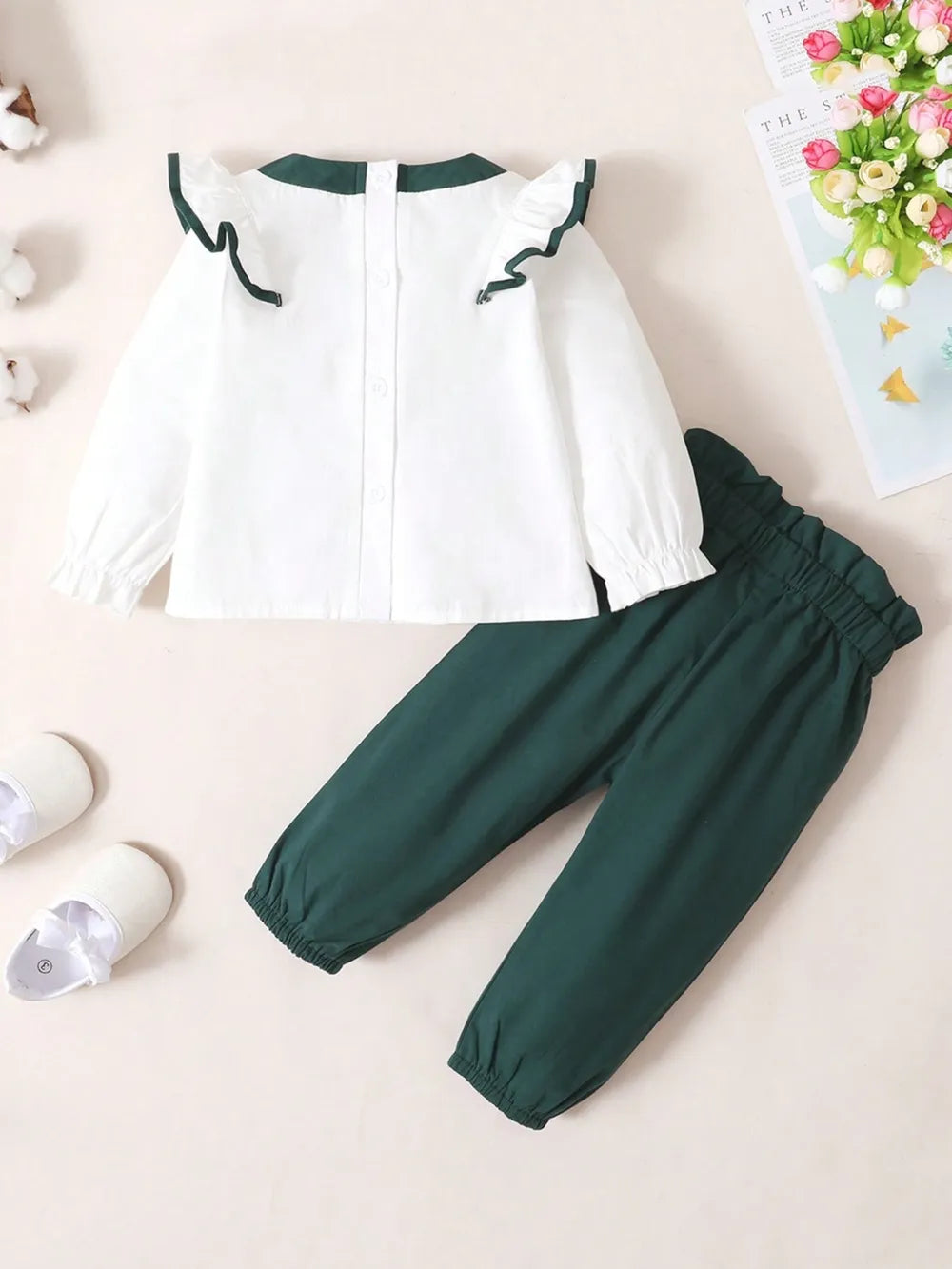 Baby girl two-piece outfit with white ruffled long-sleeve top and green bow accent, and matching green pants with coordinating bow detail