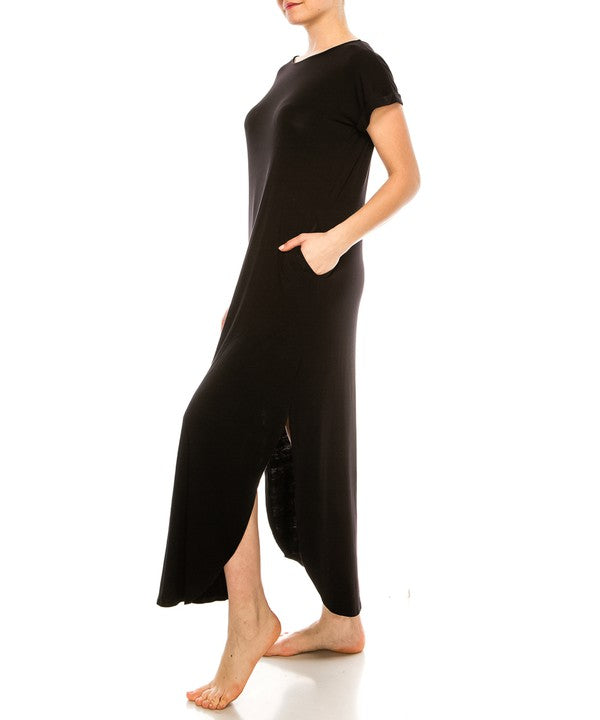 Woman wearing a black maxi dress with short sleeves, barefoot, against a white background.