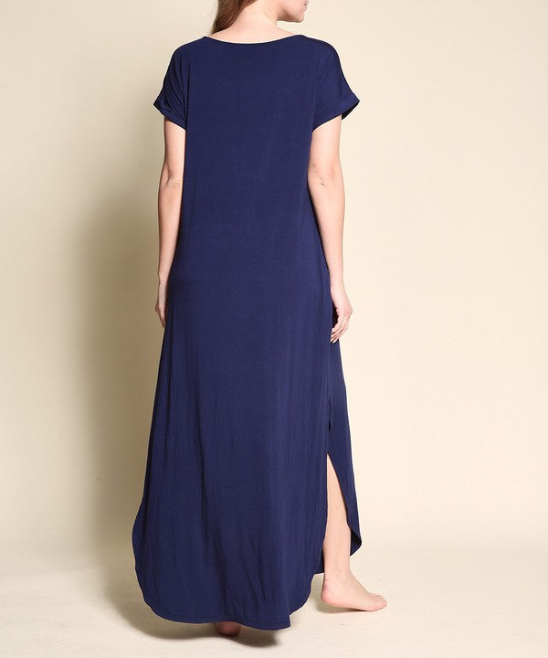 Woman wearing a navy blue maxi dress with short sleeves, barefoot, against a white background.