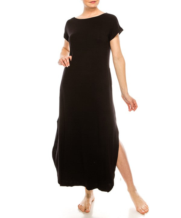 Woman wearing a black maxi dress with short sleeves, barefoot, against a white background.