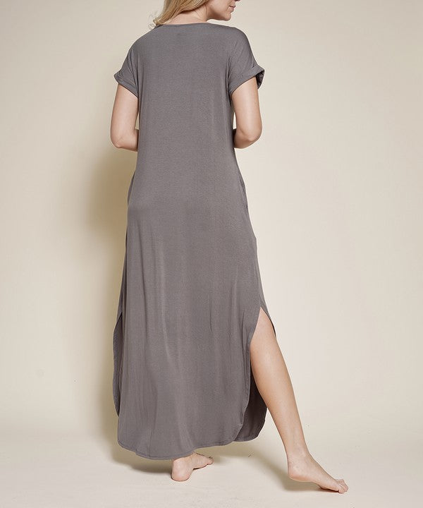 Woman wearing a grey maxi dress with short sleeves, barefoot, against a white background.