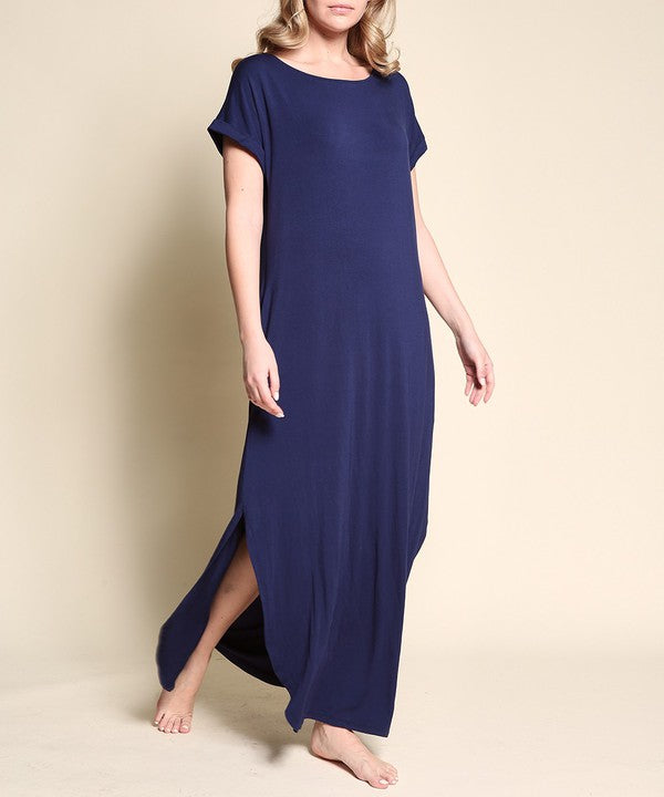 Woman wearing a navy blue maxi dress with short sleeves, barefoot, against a white background.