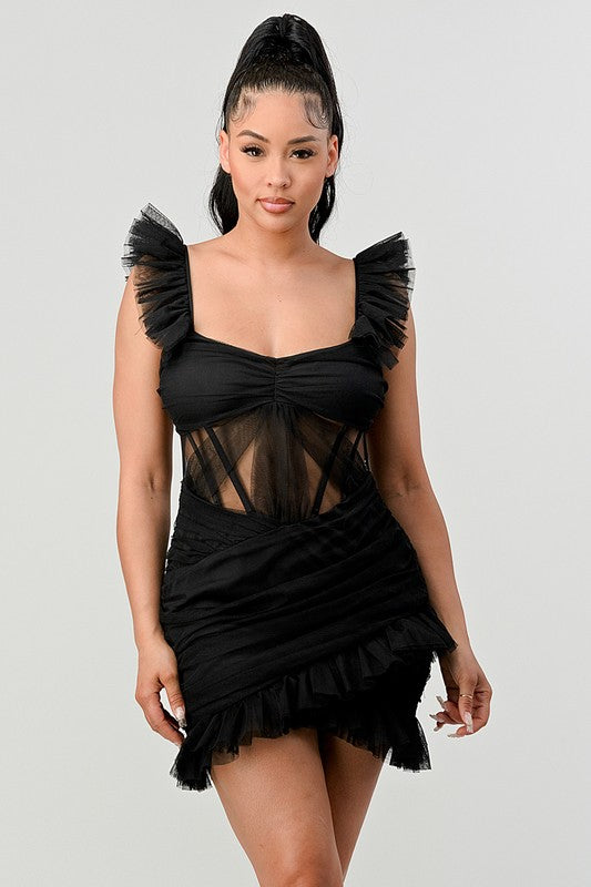 The dress is a chic black mini with a fitted silhouette, sheer paneling at the bodice, and dramatic ruffled cap sleeves that add a flirty, edgy touch.