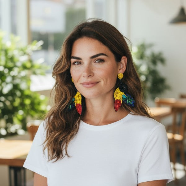Woman wearing a plain white t-shirt and vibrant, multicolored statement earrings with a tropical-inspired design, bold, artistic, and perfect for adding flair to a casual look.