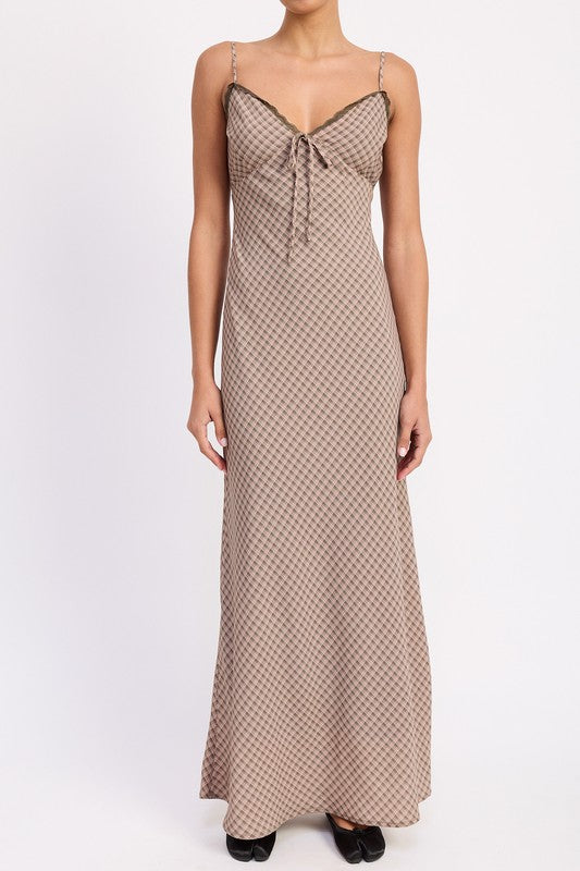 The dress is a form-fitting, floor-length maxi with a soft, neutral taupe color and a delicate, textured fabric