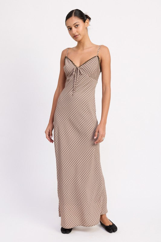 The dress is a form-fitting, floor-length maxi with a soft, neutral taupe color and a delicate, textured fabric