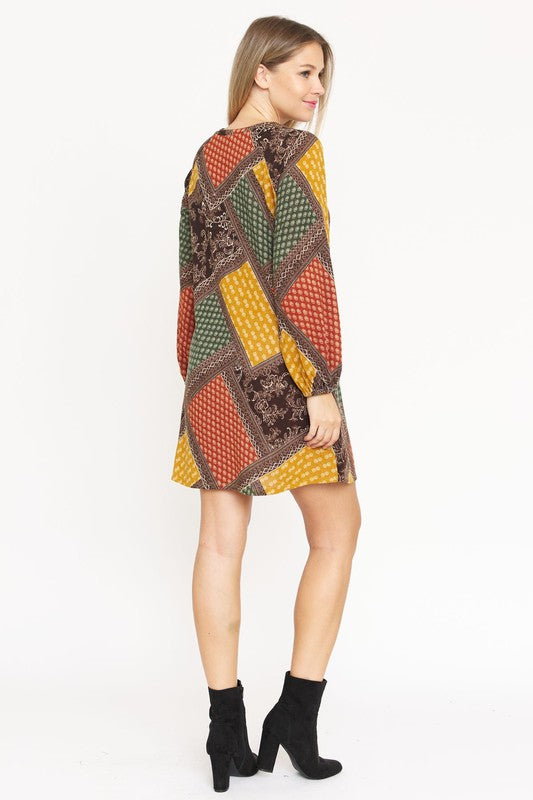 A color-blocked patchwork dress with bold, geometric patterns in red, orange, blue, and black, creating a vibrant, eclectic look.