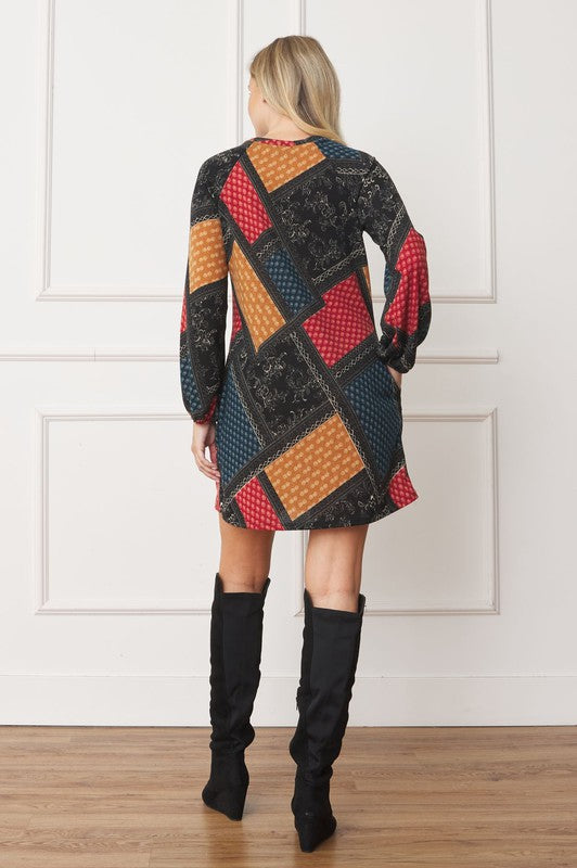 A color-blocked patchwork dress with bold, geometric patterns in red, orange, blue, and black, creating a vibrant, eclectic look.