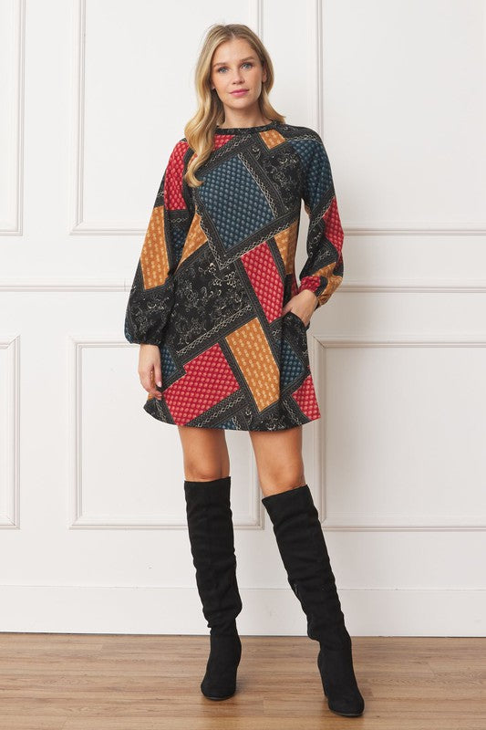 A color-blocked patchwork dress with bold, geometric patterns in red, orange, blue, and black, creating a vibrant, eclectic look.