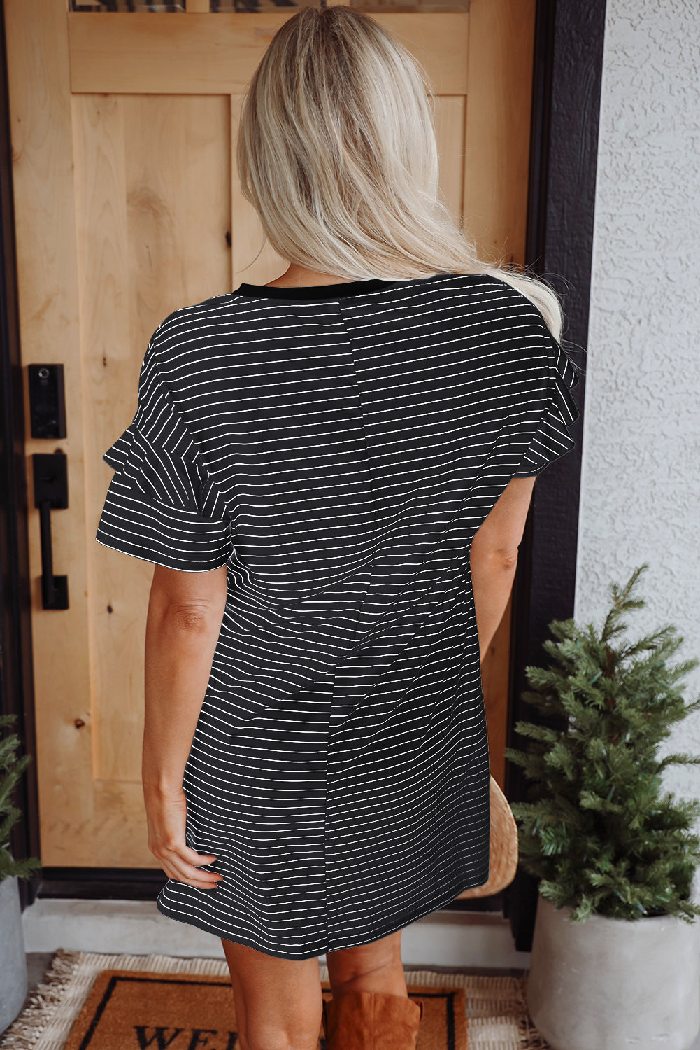 Woman wearing a black striped short-sleeve shift mini dress with ruffled sleeves