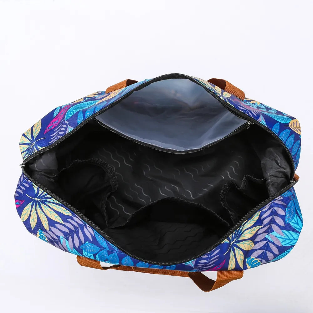 Open duffel bag with a vibrant leaf pattern in blue, purple, and yellow, featuring brown handles and a black-lined interior with elastic side pockets. Spacious and organized—great for travel or gym use.