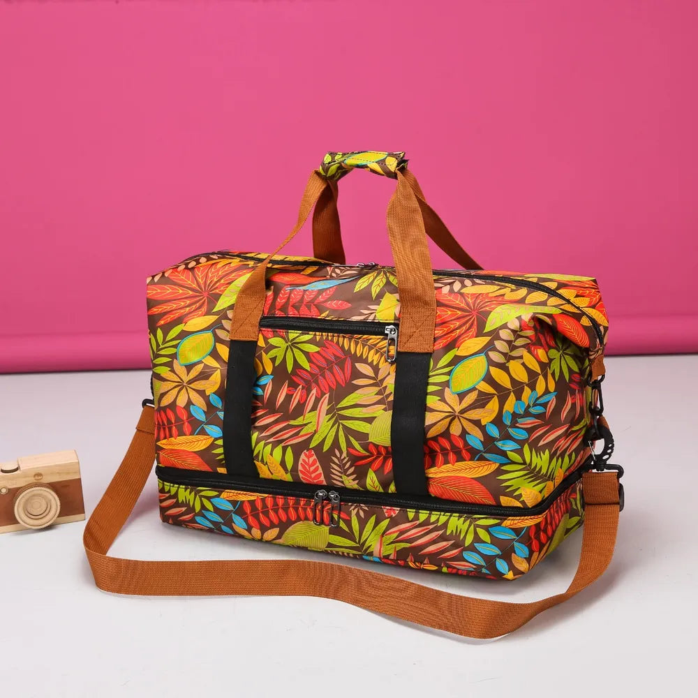 Colorful duffel bag with a vibrant leaf pattern in red, orange, yellow, green, and blue, featuring brown handles, a front zippered pocket, and black vertical straps. Set against a bright pink background—bold, playful, and perfect for travel or casual use.