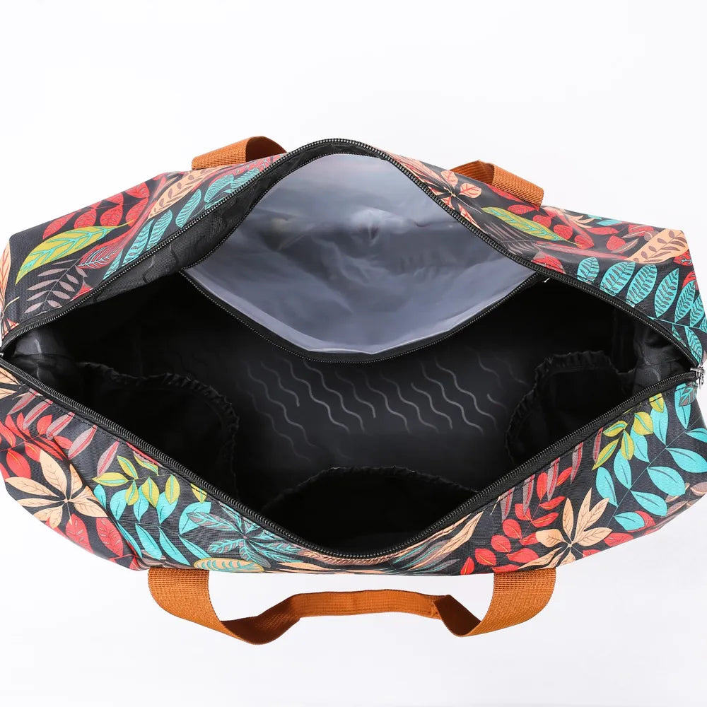 Open duffel bag with a colorful leaf pattern and brown handles, revealing a spacious black-lined interior with multiple compartments. Vibrant and practical—great for organized travel or gym use.