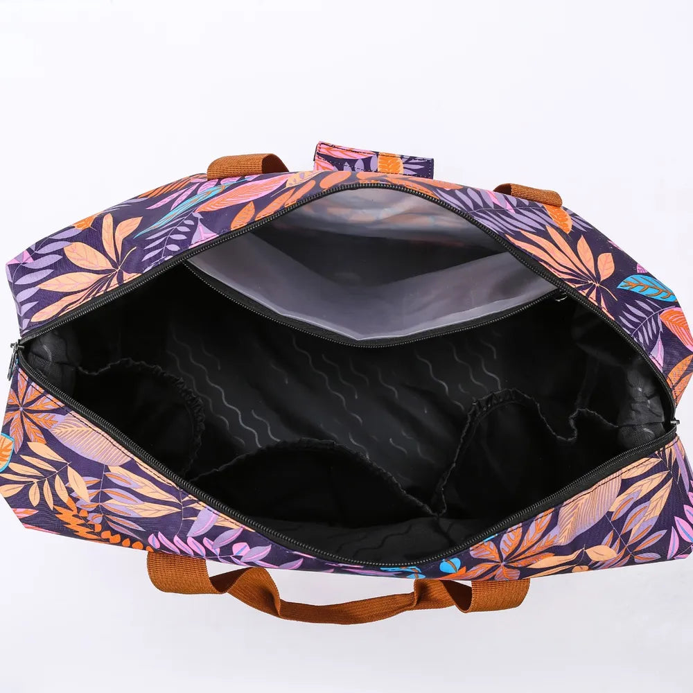 Open duffel bag with a colorful floral pattern in purple, orange, and pink, featuring brown handles and a black interior with multiple compartments, including a mesh pocket on the top flap. Functional and vibrant—ideal for travel or gym use.