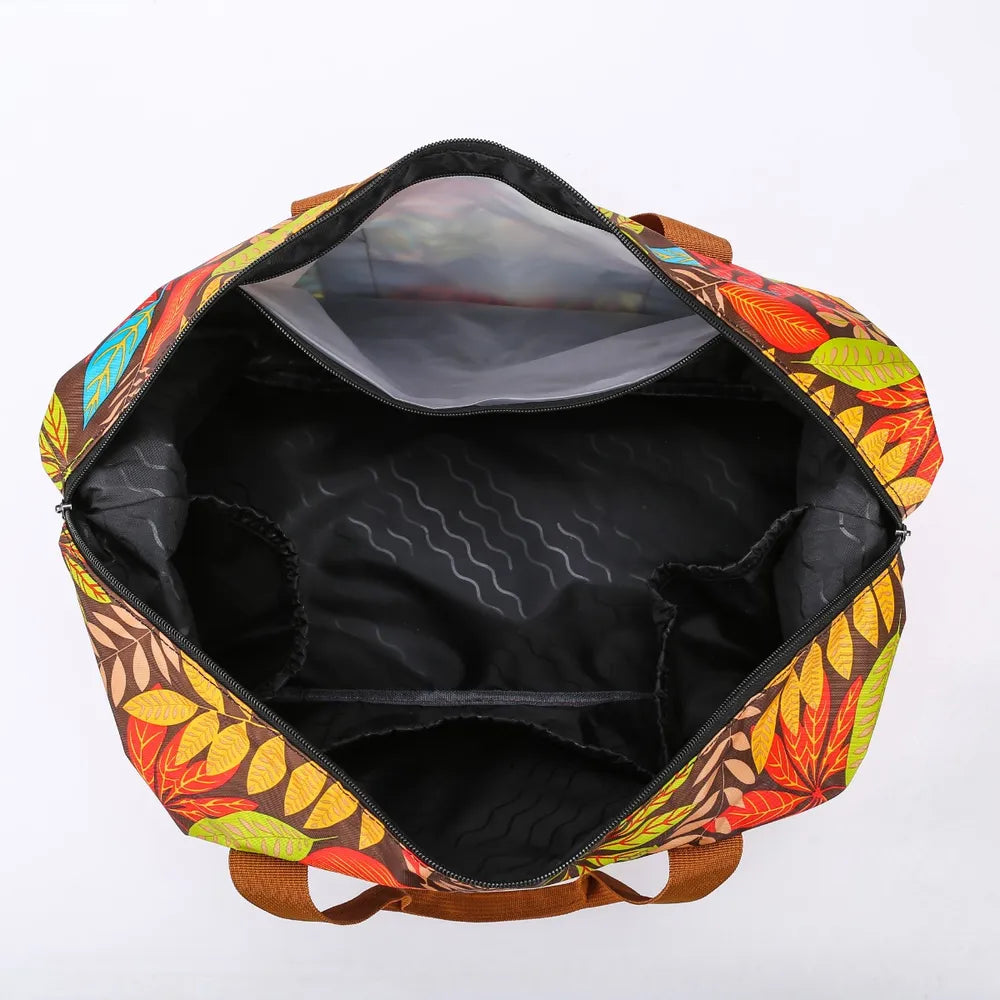 Open duffel bag with a vibrant leaf pattern in red, yellow, orange, and green, featuring brown handles and a black-lined interior with multiple side compartments. Spacious and well-organized—ideal for travel or everyday use.