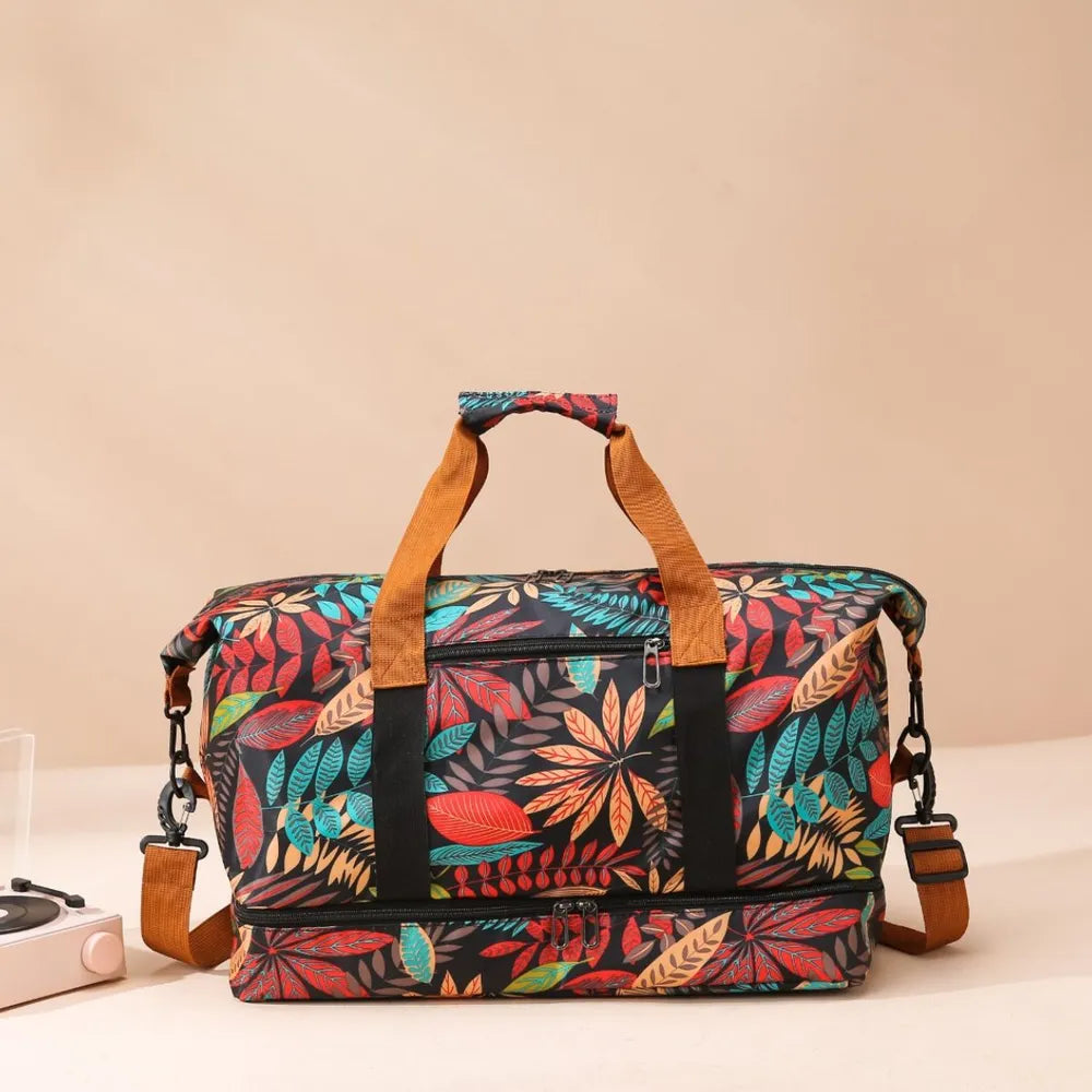 Colorful duffel bag with a vibrant leaf pattern in red, yellow, green, and blue, held by a person wearing a white cartoon t-shirt and light blue jeans. Bold and eye-catching—perfect for travel or casual outings.