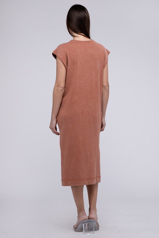 Woman models a comfortable dark tan midi dress with a relaxed fit and convenient side pockets, back view.