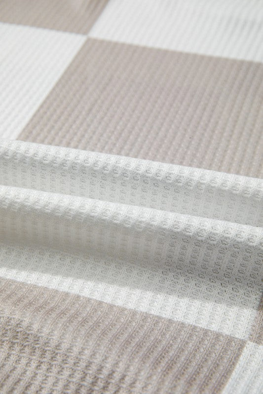 Close-up of a textured fabric with a checkered pattern in beige and white.