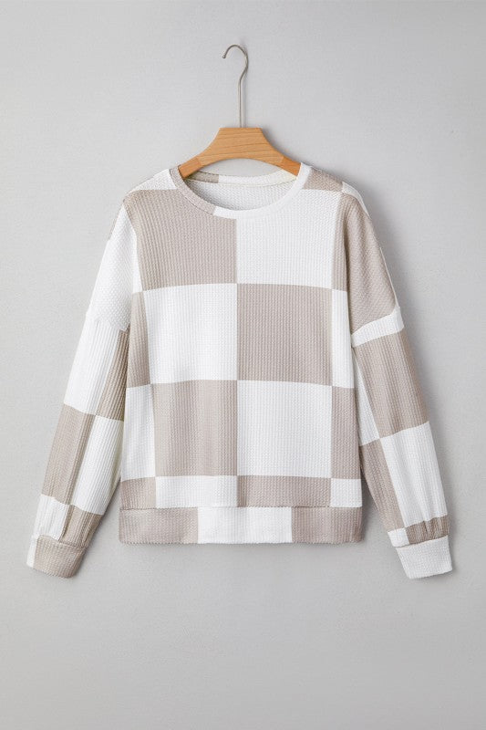 Checkered sweater on a hanger against a gray background