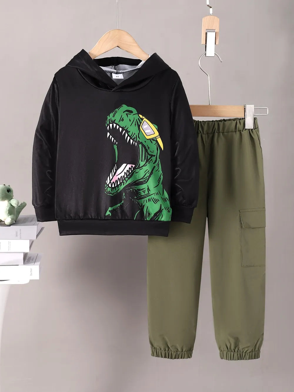 Children's hoodie with dinosaur design and green pants on a gray background
