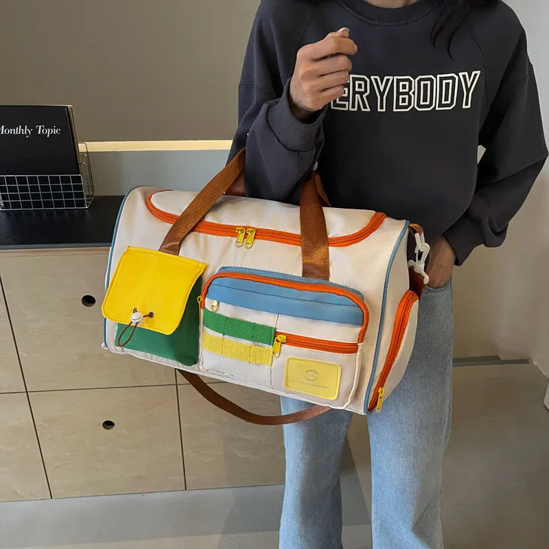 A woman holding a white duffel bag with orange zippers and brown straps, featuring colorful external pockets in yellow, green, and blue. Playful and functional design—perfect for travel, gym, or casual outings.