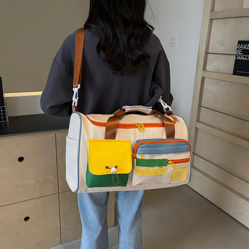 A woman hanging a white duffel bag with orange zippers and brown straps, featuring colorful external pockets in yellow, green, and blue. Playful and functional design—perfect for travel, gym, or casual outings.