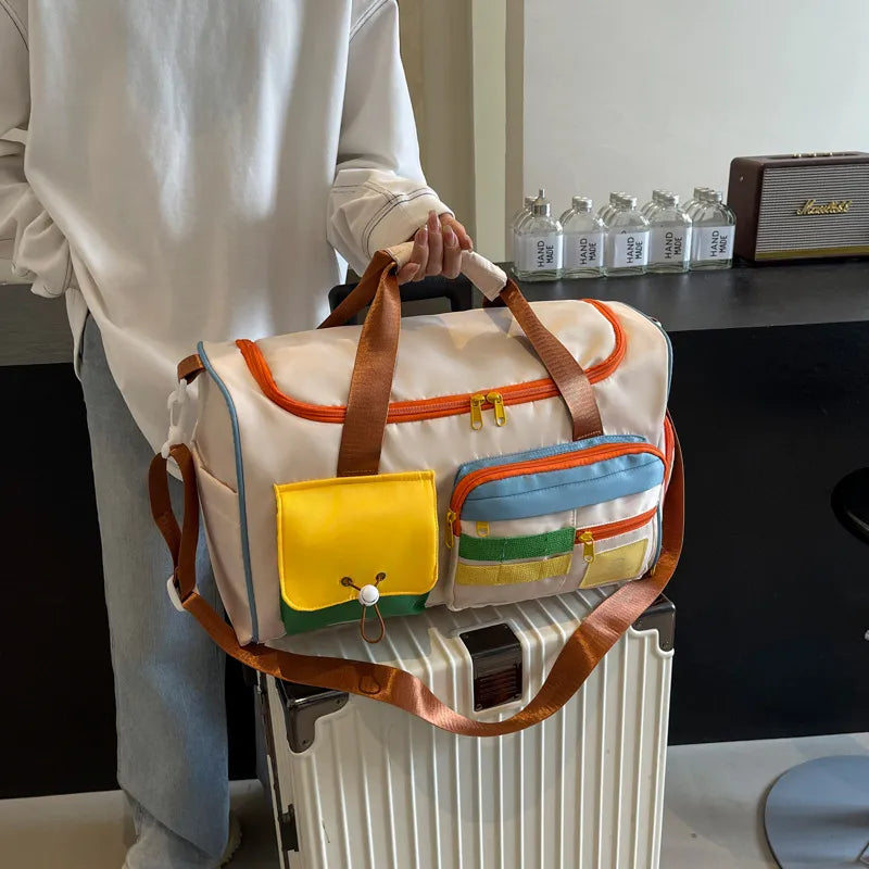 Colorful duffel bag with white base, orange zippers, and brown straps. Features multiple front pockets in yellow, green, blue, and transparent mesh for organized storage. Durable and stylish—perfect for travel, gym, or daily use.