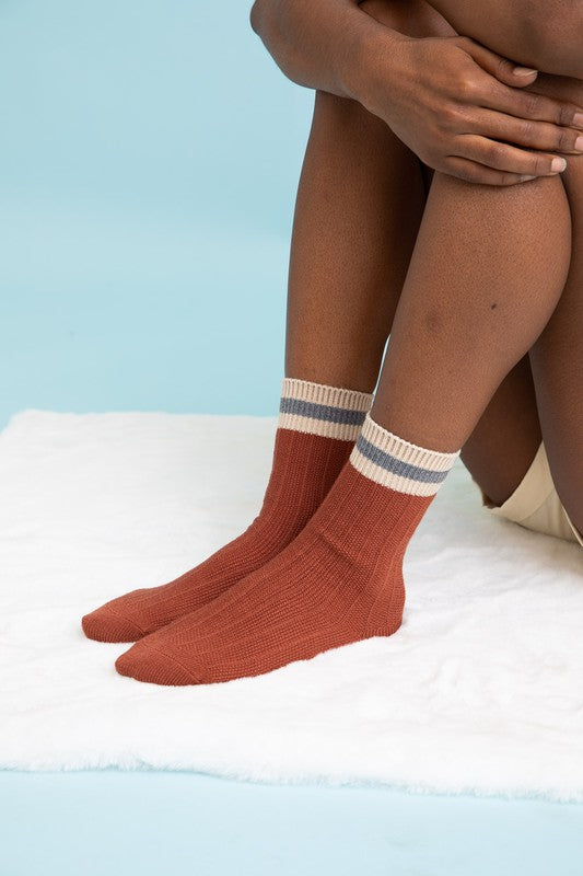Rust ribbed crew socks with striped cuffs, adding a warm tone to the collection, close-up.