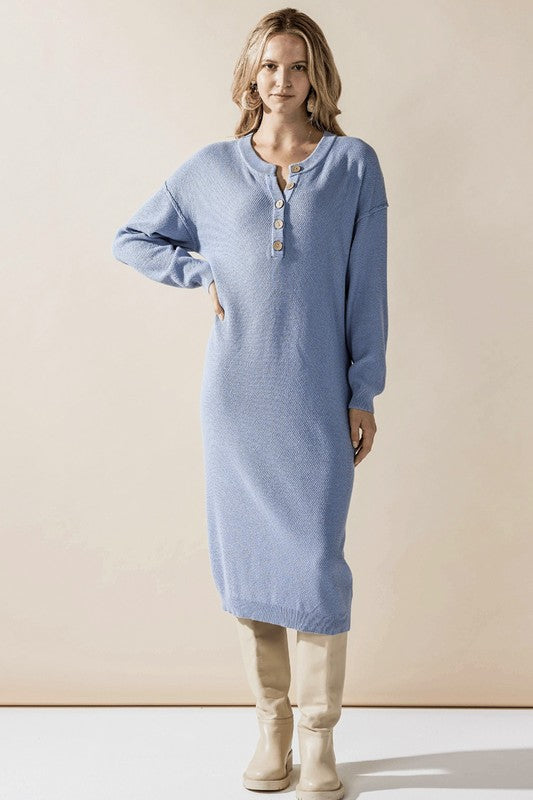 Woman wearing a button-front sweater midi dress with long sleeves and henley neckline.