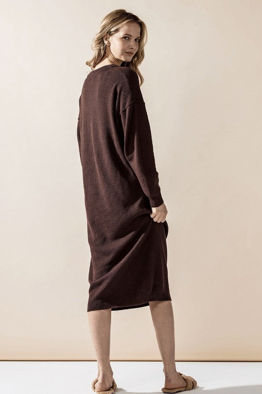 Woman wearing a button-front sweater midi dress with long sleeves and henley neckline.