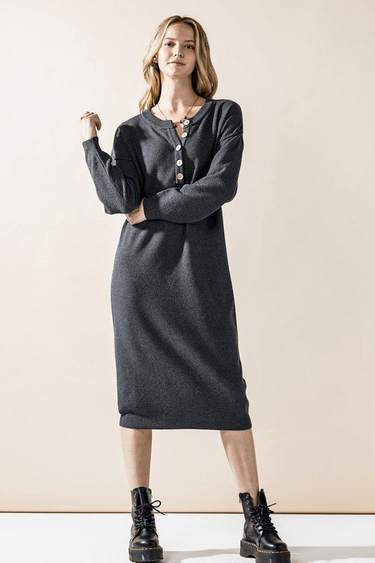 Woman wearing a button-front sweater midi dress with long sleeves and henley neckline.