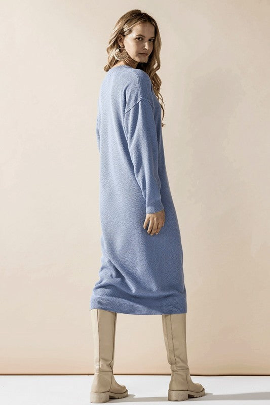 Woman wearing a button-front sweater midi dress with long sleeves and henley neckline.