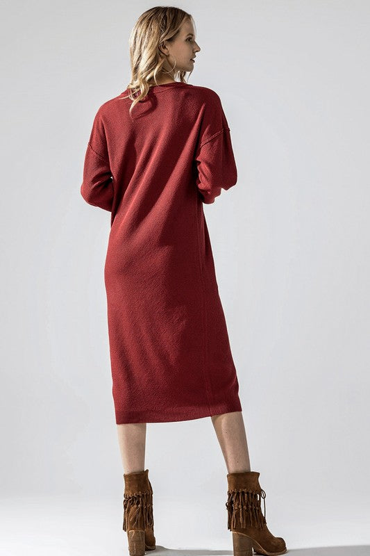 Woman wearing a button-front sweater midi dress with long sleeves and henley neckline.