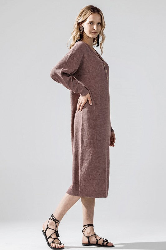 Woman wearing a button-front sweater midi dress with long sleeves and henley neckline.