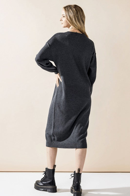 Woman wearing a button-front sweater midi dress with long sleeves and henley neckline.