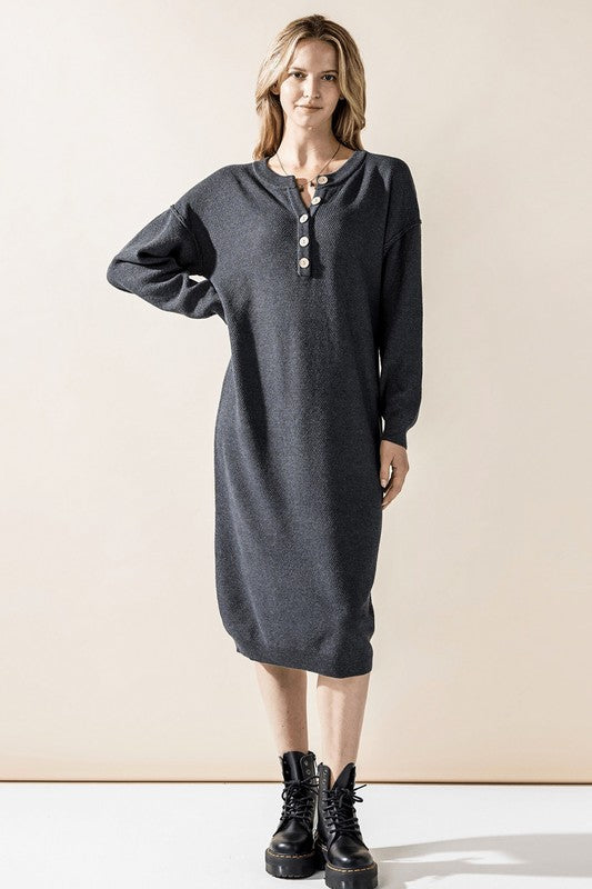Woman wearing a button-front sweater midi dress with long sleeves and henley neckline.