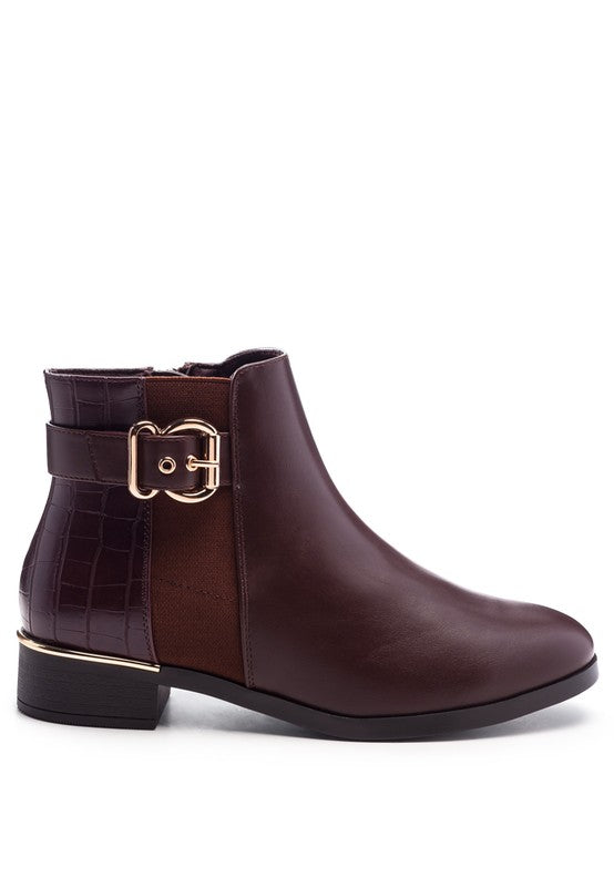 A brown decorative strap with a gold-tone buckle runs around the outer side near the ankle.