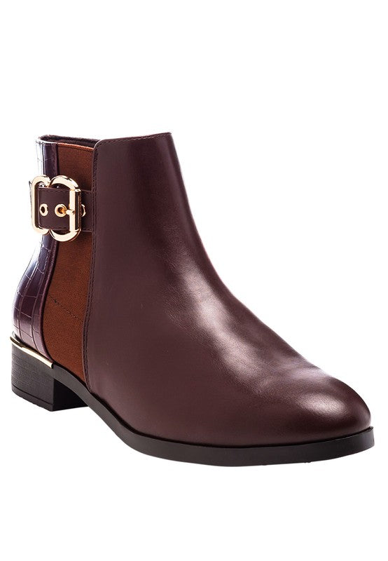 A brown decorative strap with a gold-tone buckle runs around the outer side near the ankle.