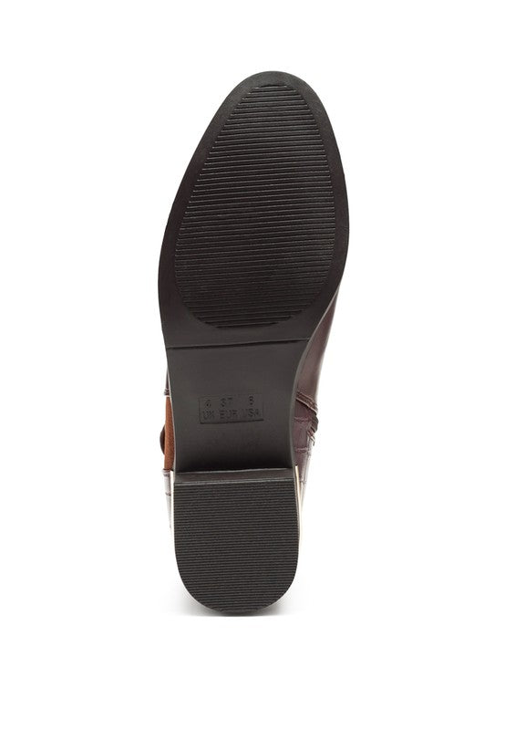 A brown decorative strap with a gold-tone buckle runs around the outer side near the ankle.