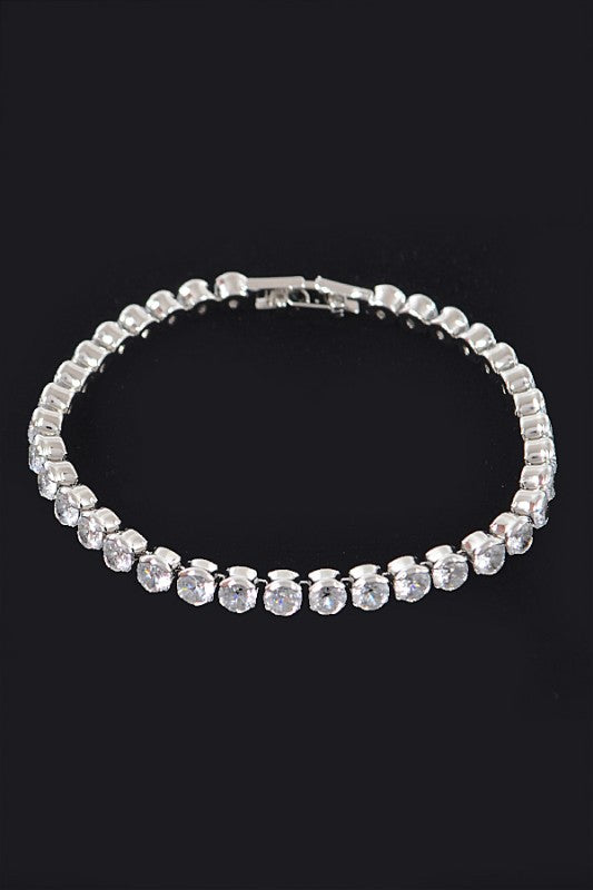 Gold tennis bracelet adorned with round-cut clear gemstones, set in a continuous row for an elegant and classic look.