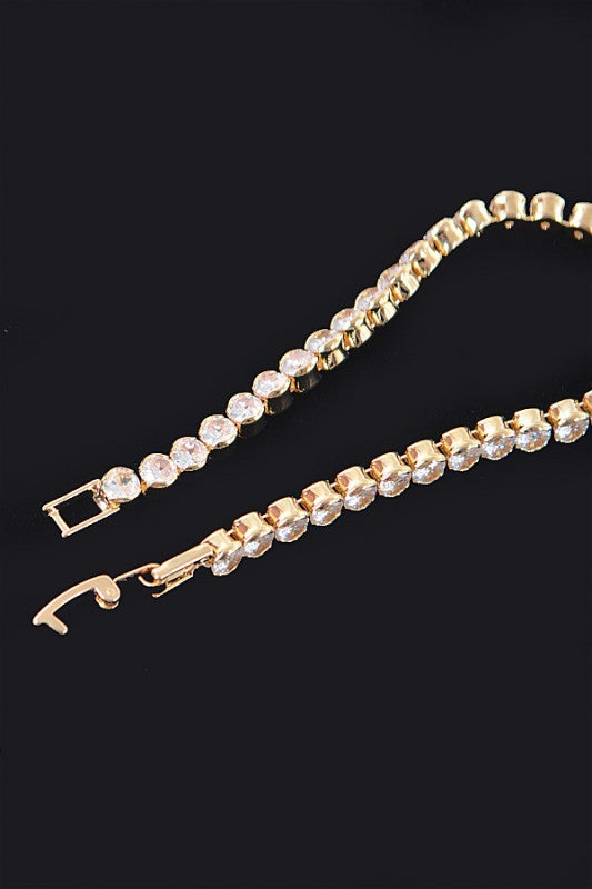 Gold tennis bracelet adorned with round-cut clear gemstones, set in a continuous row for an elegant and classic look.
