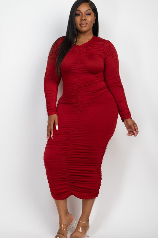 A model wears a chic burgundy ruched midi dress with long sleeves and a V-neck, perfect for an evening look.