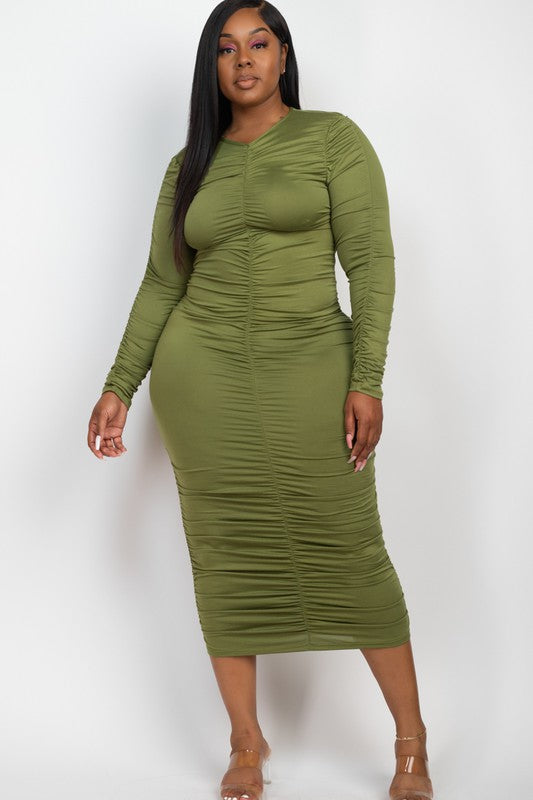 A model wears a fashionable olive green ruched midi dress with long sleeves, highlighting its curve-enhancing design.