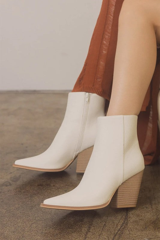 Off-white leather ankle booties featuring pointed toe, textured wood-look block heel, and tan sole trim.