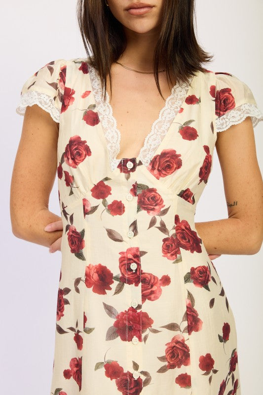 Woman models a vintage-inspired cream midi dress with red rose print, close up view.